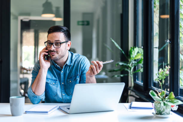 istock Entrepreneur discussing on cellphone while working on laptop at home office 1405602589