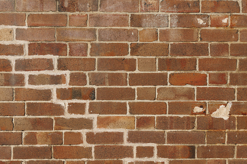 Section of an old faded brown brick wall.