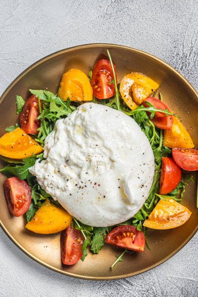 istock Italian Burrata cheese with cherry tomatoes and fresh arugula. White background. Top view 1405604372