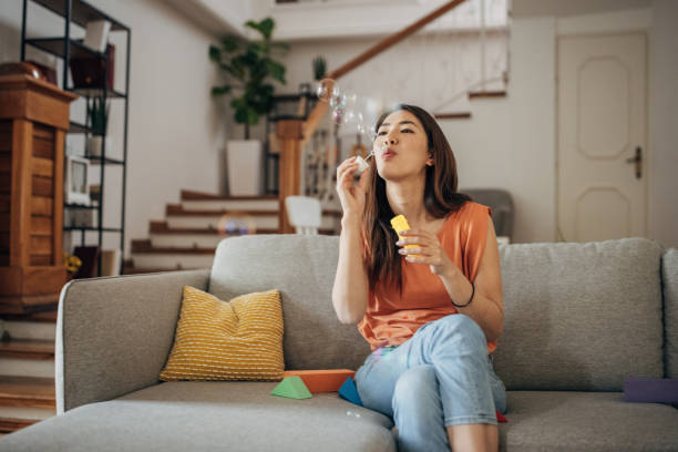 istock Japanese woman blowing bubbles while sitting on sofa 1405607807