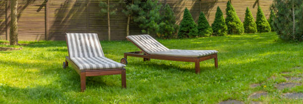 istock Lounge chairs on the backyard in a beautiful garden. Two empty sunbeds on the grass. 1405608758