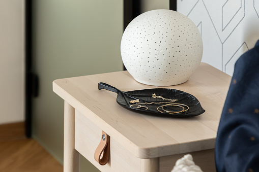 Close-up on stylish decoration on wooden bedside table with small drawer