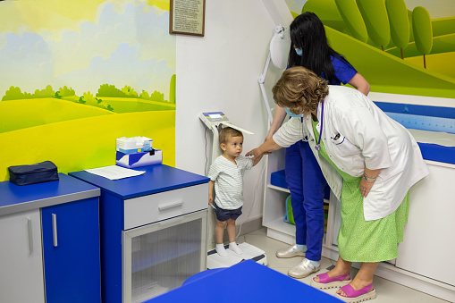 A mature female doctor and a nurse preparing to examine a little boy