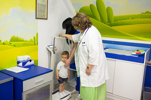 A mature female doctor and a nurse preparing to examine a little boy