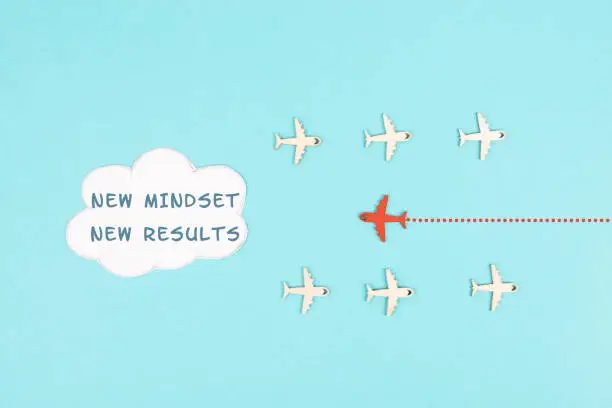 Red airplane is flying to the cloud with the words new mindset new results, changing lifestyle, coaching and improvement concept, positive thinking