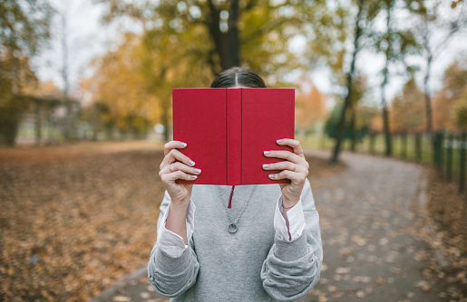 A young woman, who is a book lover, spends a rainy autumn day in the park