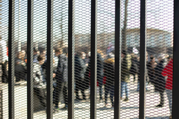 Fence behind which people. Black fence in public place. People are in jail.