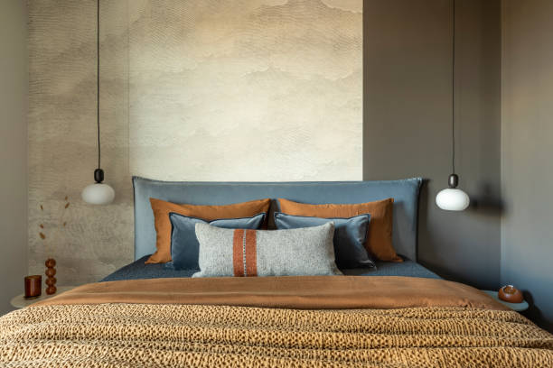 istock Stylish composition of modern bedroom interior. Bed, creative lamp and elegant personal accessories. Concrete wall. Brown sheeets. Minimalistic masculine concept. Template. 1405613908