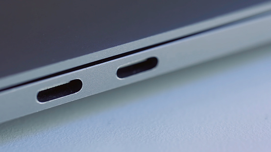 Close up of elegant modern laptop details. Concept of modern technologies, USB port of a computer lying on white flat surface.