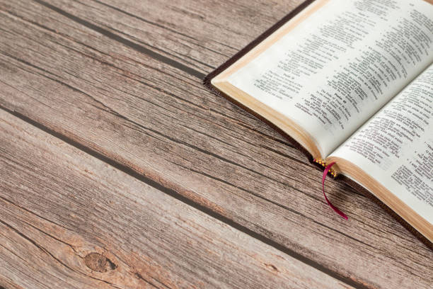 istock Open Holy Bible Book with golden pages on a rustic wooden table with copy space 1405615968