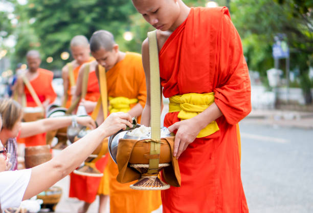 luang prabang, laos - 19 czerwca 2022 r.: buddyjska ceremonia dawania jałmużny lub tak wczesnym rankiem. jest to wieloletnia tradycja w kulturze buddyjskiej laosu i święta ceremonia dla mieszkańców i mnichów. a teraz dzień został przedłużony dla - alms zdjęcia i obrazy z banku zdjęć