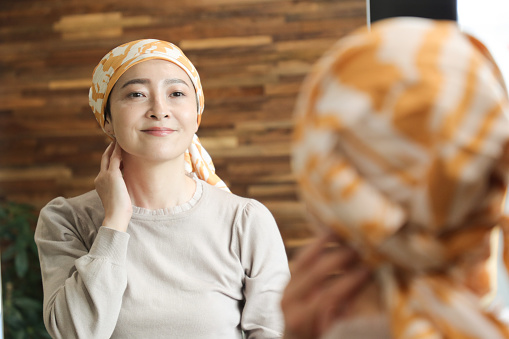 Cancer patient see herself in the mirror.  She enjoy dressing up in style by wrapping bandanas