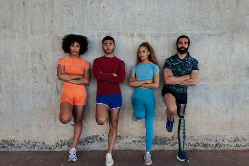 Four young multiracial diverse people in a city street before starting a workout, posing with arms folded