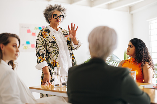 Businesswoman having a discussion with her colleagues during a meeting. Mature businesswoman sharing her ideas with her team. Multicultural businesswomen working together in an all-female startup.