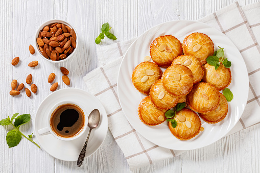 Netherland almond cookies filled with marzipan and almonds nuts paste, gevulde koek, on white plate on white wood table, horizontal view from above