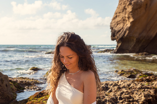 brunette woman in a white bathing suit on Santa Cruz beach, near Torres Vedras. Having fun. Feeling happy. Enjoying her afternoon at the beach