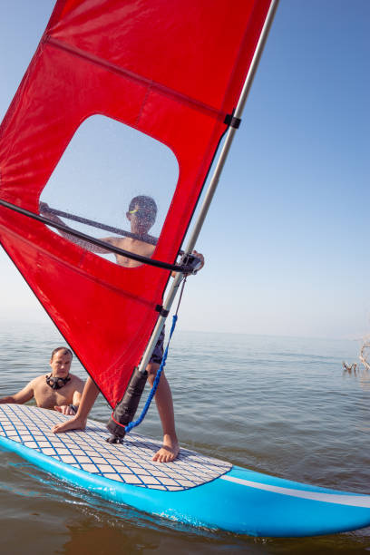 istock Learn how to windsurf. Father giving his son a windsurfing lesson outdoors in the lake. 1405622962