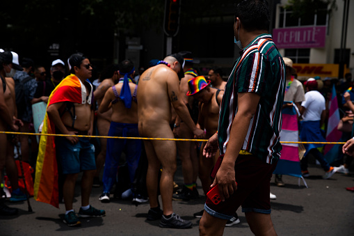 Nudist men prepare minutes before to start the gay pride parade, while a. man crosses and watches them. XLIV National March of Pride and Dignity LGBTTT In Mexico City. June 25, 2022. ( OZ Photo/Octavio Sanchez)