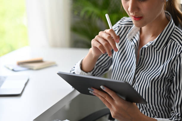 istock Close up with makeup woman holding the tablet and electronic pen ready to write something, office background, business and financial concepts. 1405624097