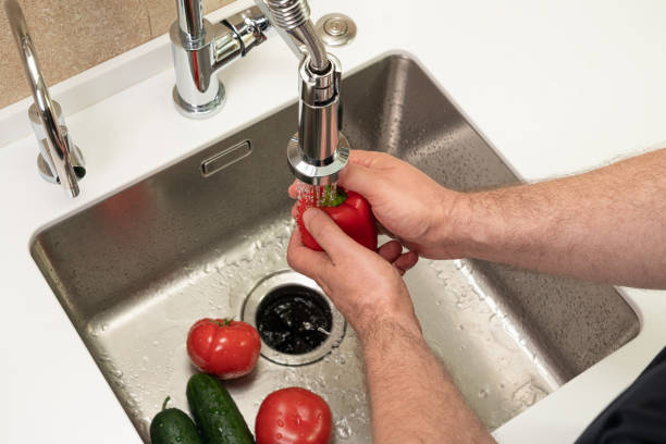 istock man washes vegetables in the kitchen over the sink 1405624808