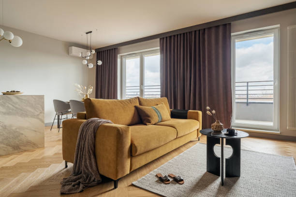 istock Creative and modern open space interior design with yellow sofa, grey carpet and coffee table . Grey carpet on the herringbone parquet with coffe table, brown curtain in windows. Template. 1405627068