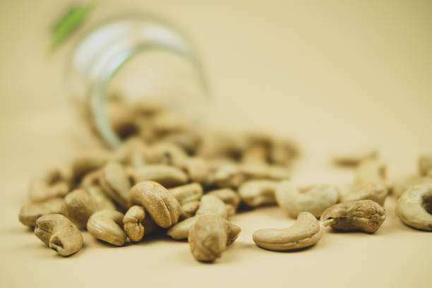 istock Peeled cashew nuts are scattered from glass bottle on table 1405627855