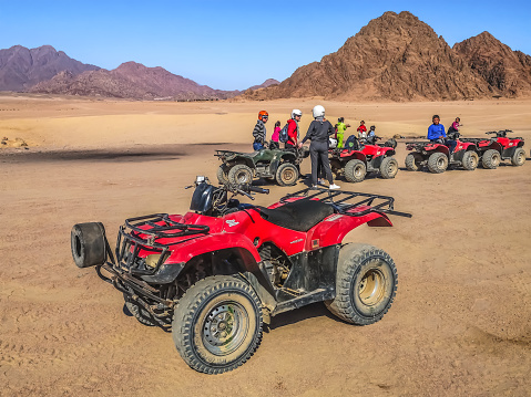 Sharm El Sheikh, Egypt - January 21, 2020: Light utility vehicles caravan with adult people near Bedouin children in the Sinai desert near Sharm El Sheikh. Active entertainment for tourists
