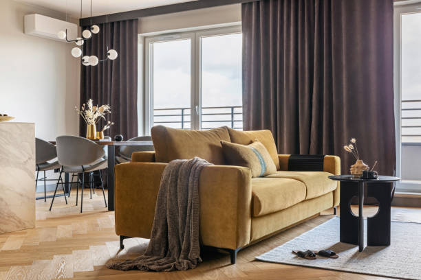 istock Creative and modern open space interior design with yellow sofa, grey carpet and coffe table . Grey carpet on the herringbone parquet with coffe table, brown curtain in windows. Template. 1405630643