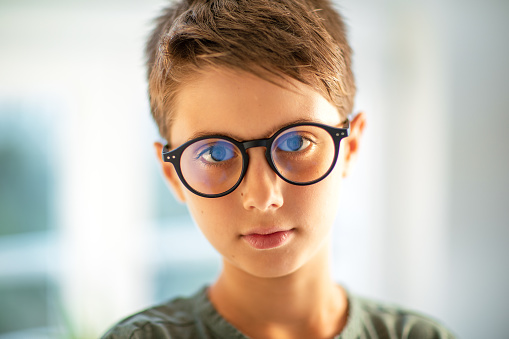 Emotional portrait of a boy looking straight at the camera wearing black frame glasses