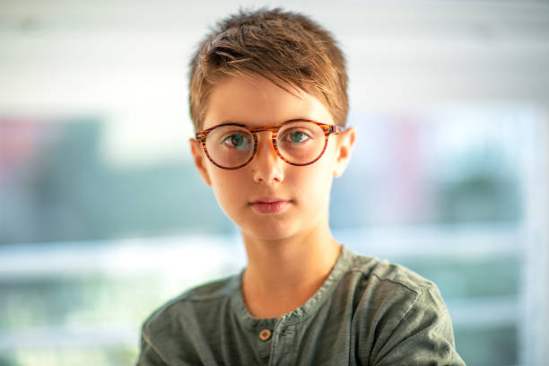 Emotional portrait of a boy looking straight at the camera wearing amber frame glasses