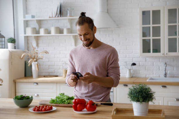 istock Happy cheerful millennial guy cooking salad in home kitchen 1405631692