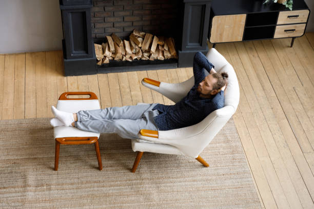 istock Calm hipster man relaxing in comfortable armchair at fireplace 1405631713