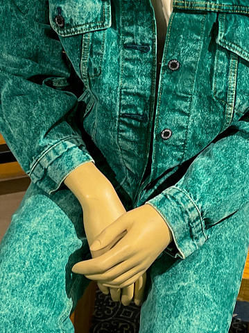Stock photo showing department store clothes department display of plastic mannequin sat wearing green denim jacket and jeans.