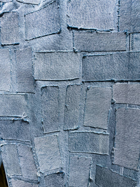 Full frame image of homemade, customised, bleached patchwork blue denim jeans, elevated view Stock photo showing close-up, elevated view of a pair of blue denim jeans sporting a customised design of bleached patches of fabric swatches. patchwork stock pictures, royalty-free photos & images