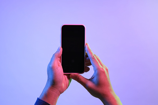 The Asian man hands holding the smart phone under the vivid color.