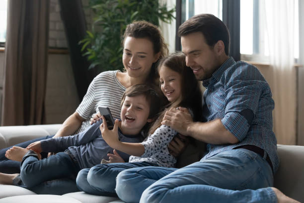istock Happy young parents with kids using smartphone at home together 1405636317
