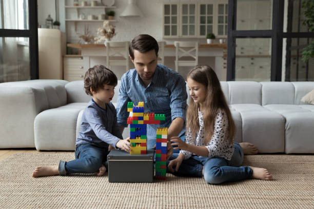 istock Caring father with little son and daughter playing on floor 1405636326