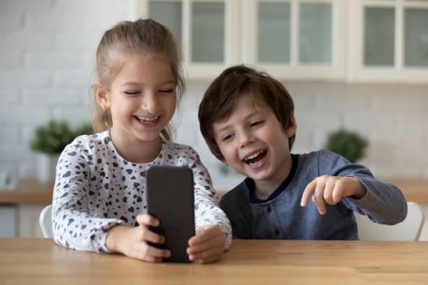 istock Overjoyed little sister and brother using smartphone, having fun 1405636389