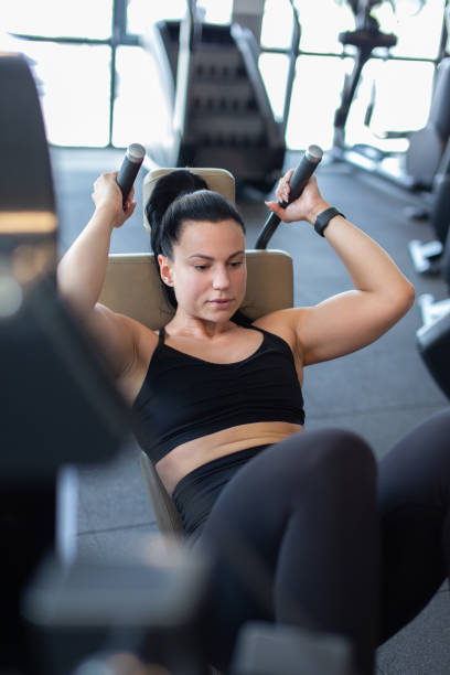 istock Young woman in gym doing crunches on machine 1405637744