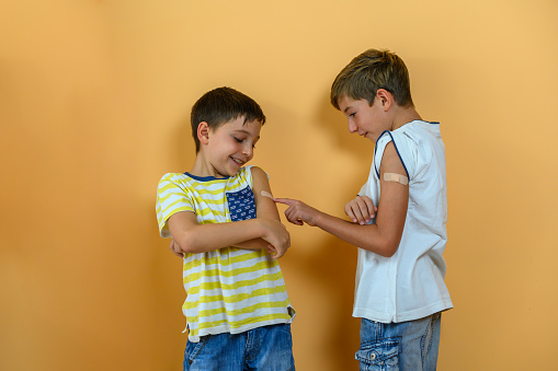 Two kids have fun with a vaccine band-aid on their arm