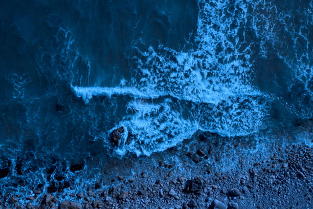 istock Moonlight beach: sea waves splashing on a rocky beach 1405639237