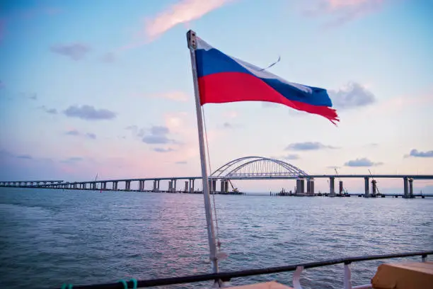 sea sunset, view of the Crimean bridge, the flag of Russia on the yacht, photo from the yacht