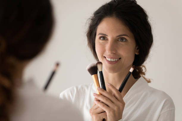 istock Happy young woman holding makeup brushes in hands. 1405640964
