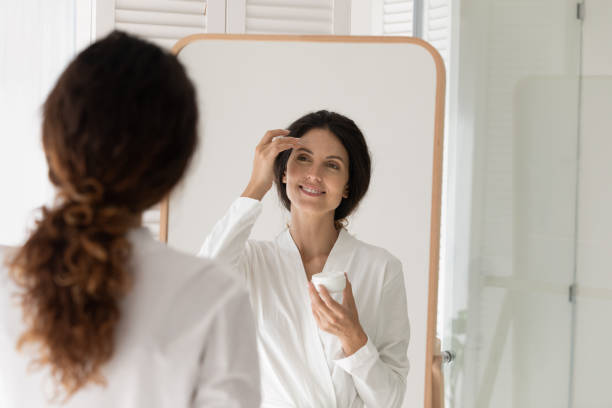 istock Happy young woman applying moisturizing cream on face. 1405640993