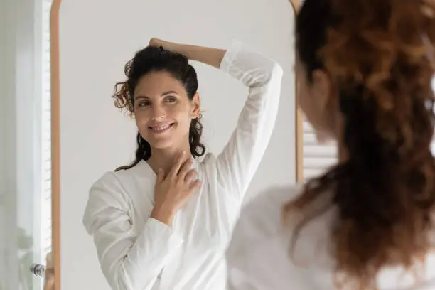 Photo of Smiling young hispanic woman looking in mirror.