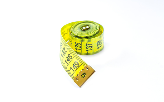 Yellow measuring tape isolated on white background close-up