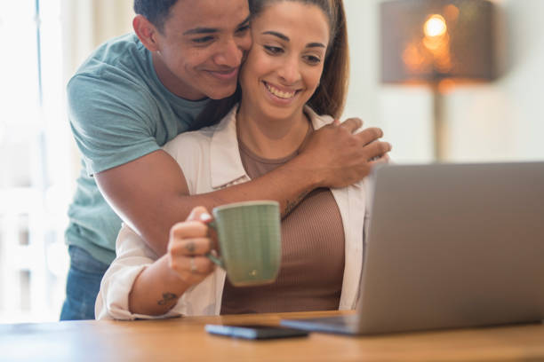 istock Man Embracing Woman Using Laptop On Table At Home 1405641510