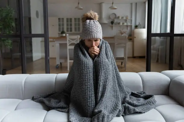 Photo of Latina female shiver at freezing flat in warm cap blanket