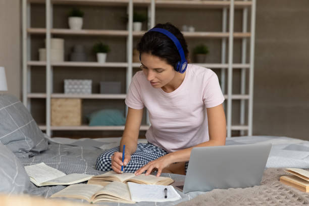 istock Attentive latin lady student in headset study literature taking notes 1405643479
