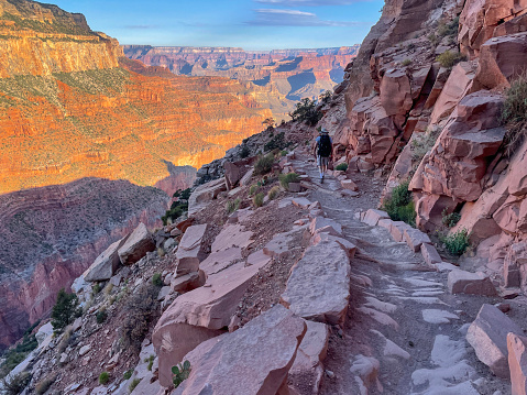 Hiker with backpack walking at sunrise at Grand Canyon, on the South Kaibab trail.